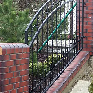 Ceglana ściana i metalowe ogrodzenie, zielone liście