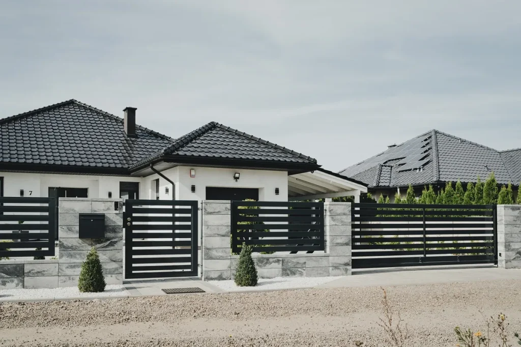 Dom z czarnym dachem i ogrodzeniem