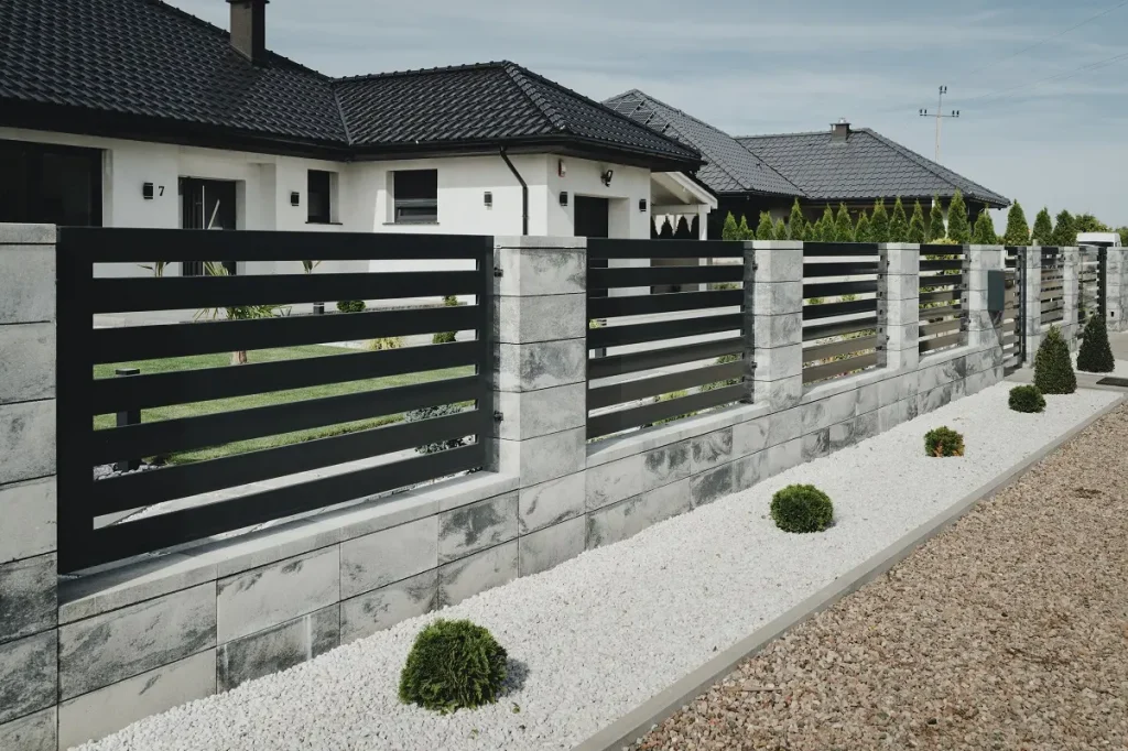 Nowoczesne ogrodzenie przed domem z kamienia i metalu.