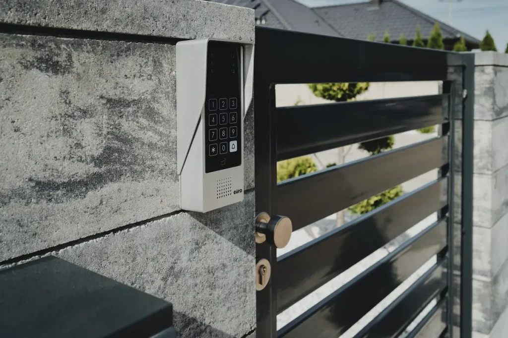 Domofon na murze przy furtce z kodem PIN.