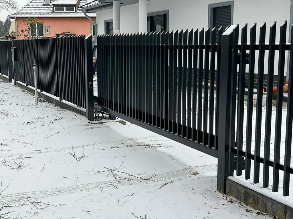 Czarny metalowy płot na zaśnieżonym podwórku