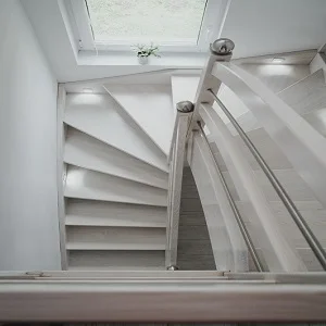 Białe schody spiralne z poręczą w domu