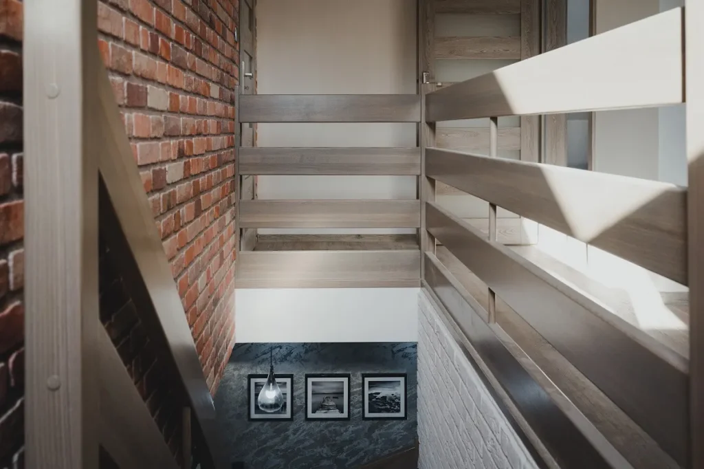 Nowoczesna klatka schodowa z cegłą i zdjęciami na ścianie.