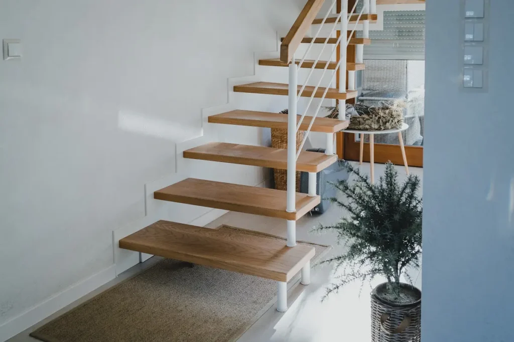 Drewniane schody w nowoczesnym wnętrzu z rośliną.